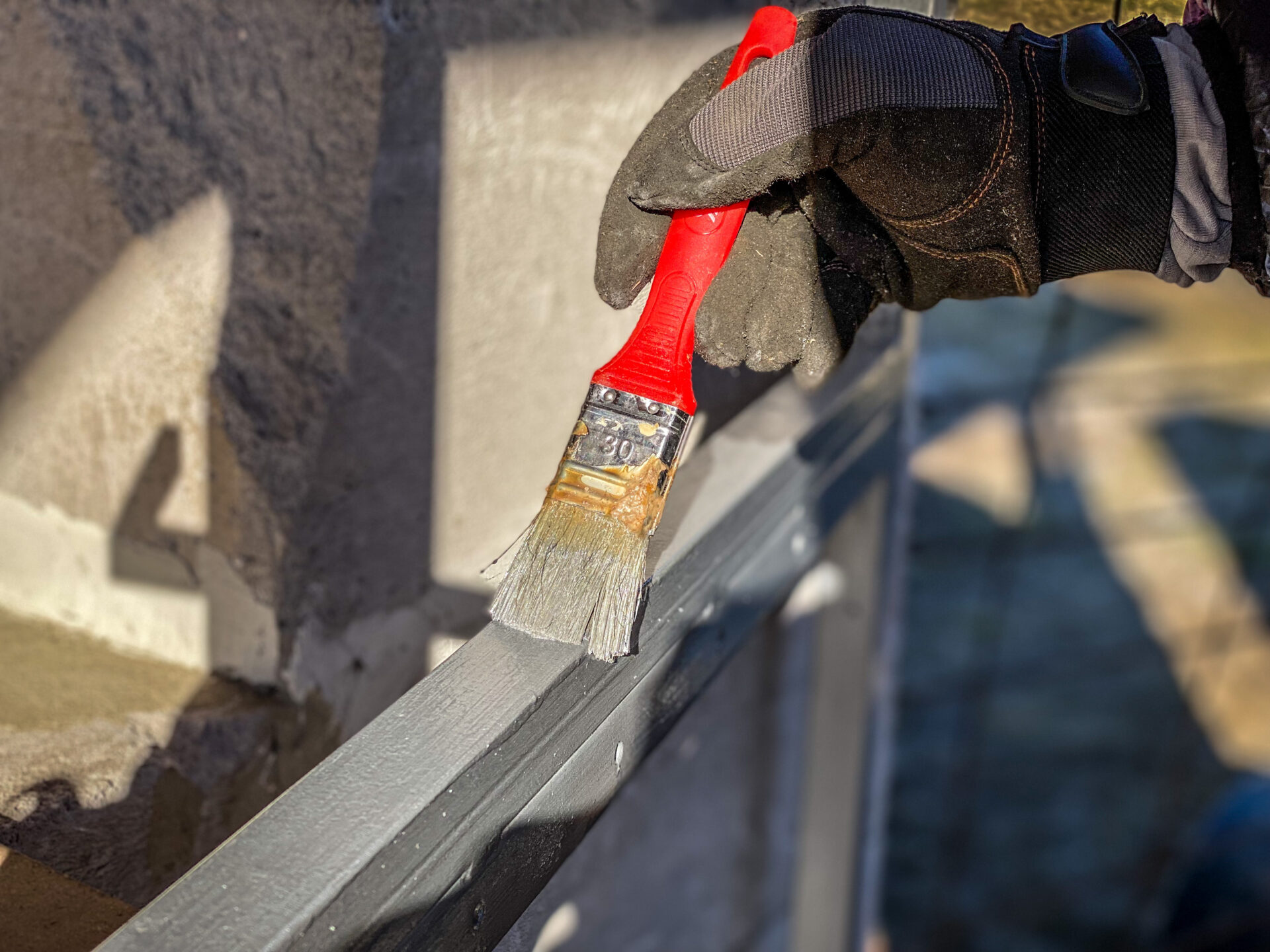 Closeup of a hand in gloves painting a gray metallic handrail with a brush applicazione eter fer
